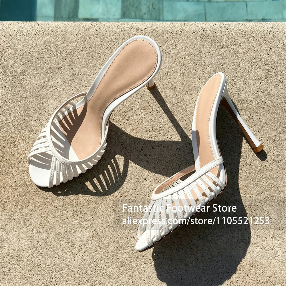 Vivodeco white mule sandals with narrow toe straps, open backs, rounded toes, and slim stiletto heels displayed on a sunlit concrete surface